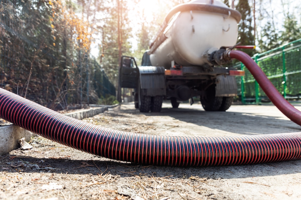 Sewer hose connected to truck emptying sewer